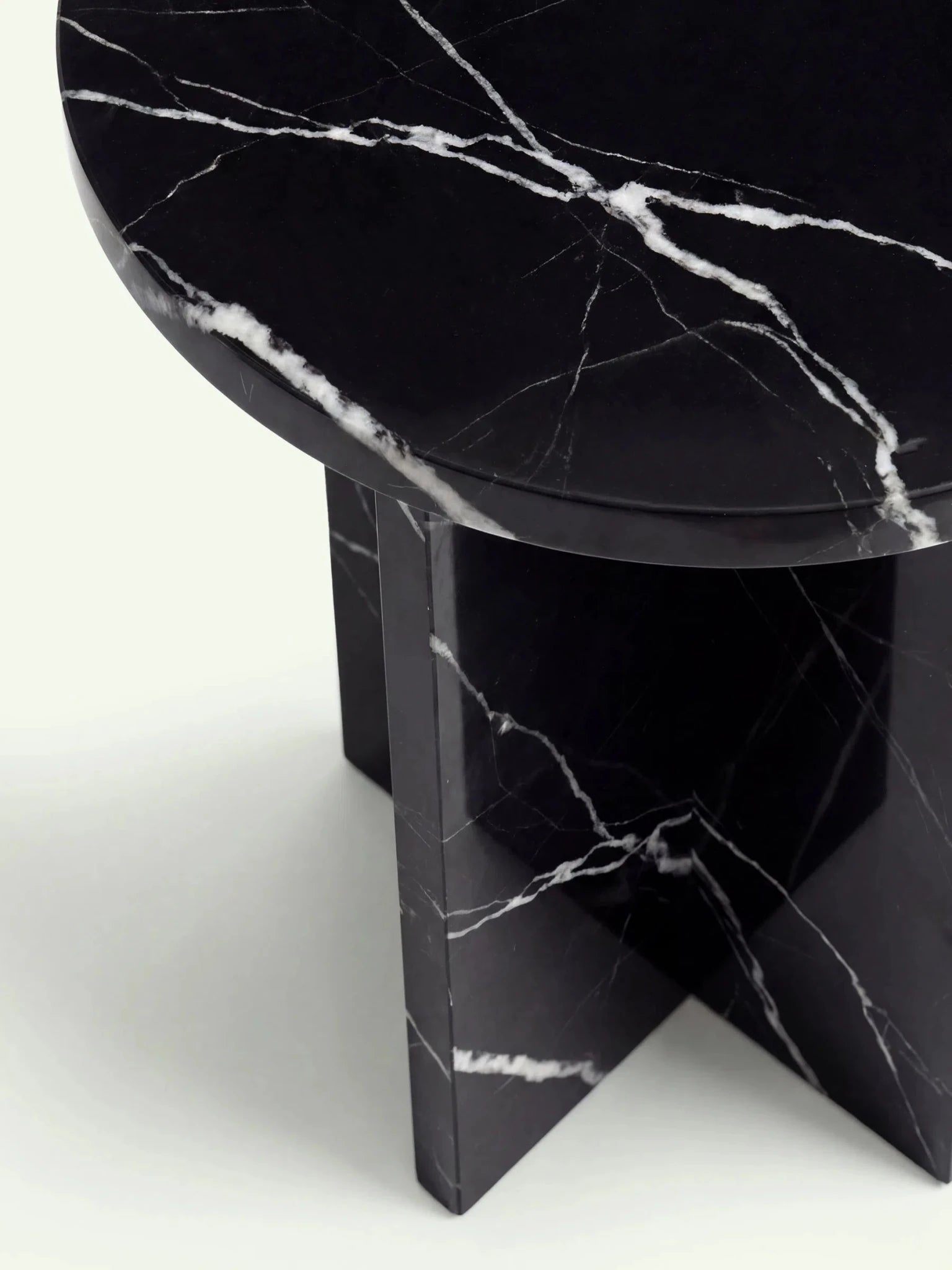 Nahaufnahme der polierten Rundkante und der glänzenden Oberfläche des Nero Marquina Marmortischs Hillu.