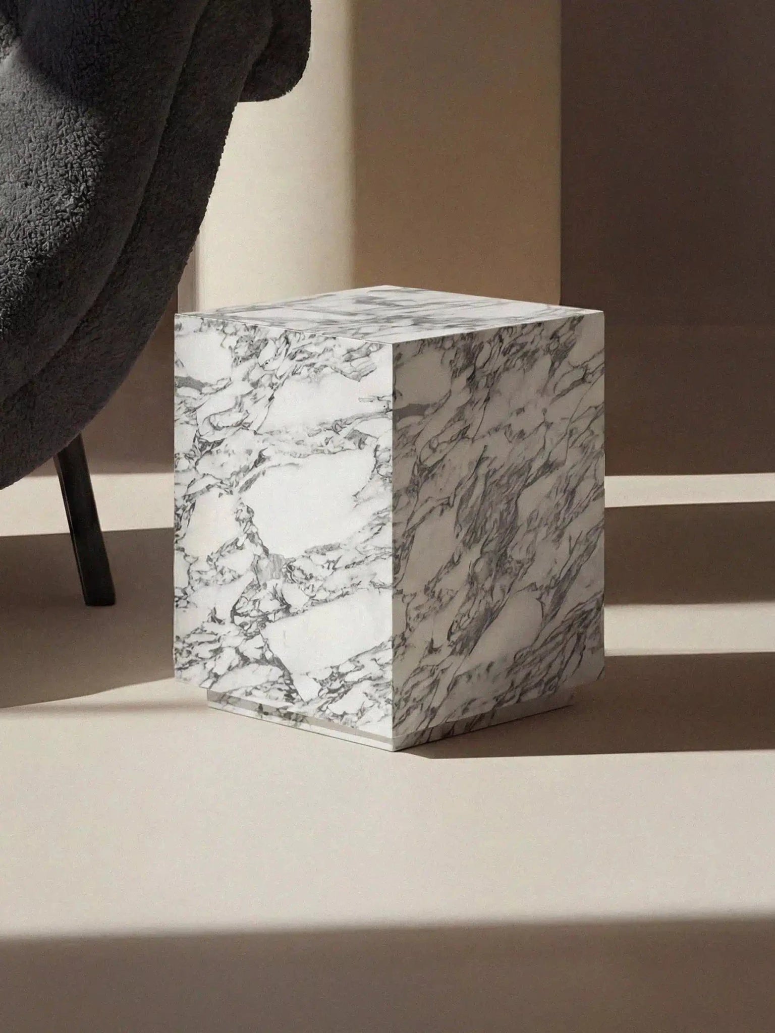 Design-Beistelltisch Pella aus Arabescato Marmor in einer stimmungsvollen Raumsituation mit Licht- und Schattenspiel.