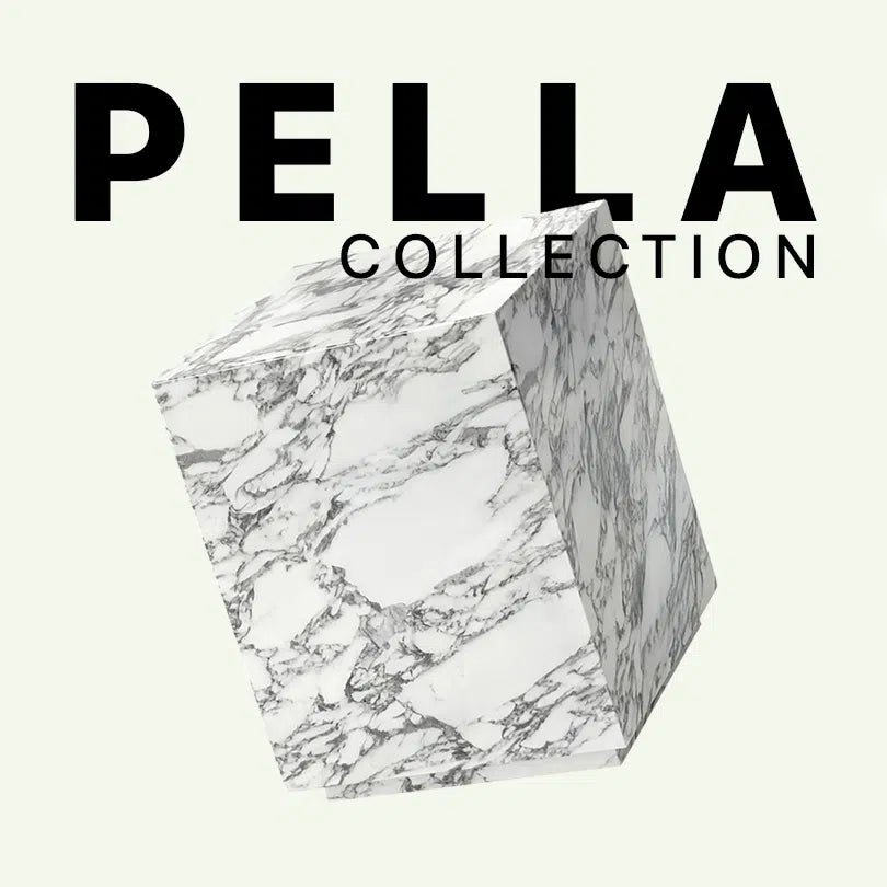 Werbegrafik für den Pella Beistelltisch von Menelame aus Arabescato Marmor. Das Bild zeigt den massiven, kubischen Tisch mit seiner markanten grau-weißen Maserung vor dem Schriftzug „Pella Collection“.
