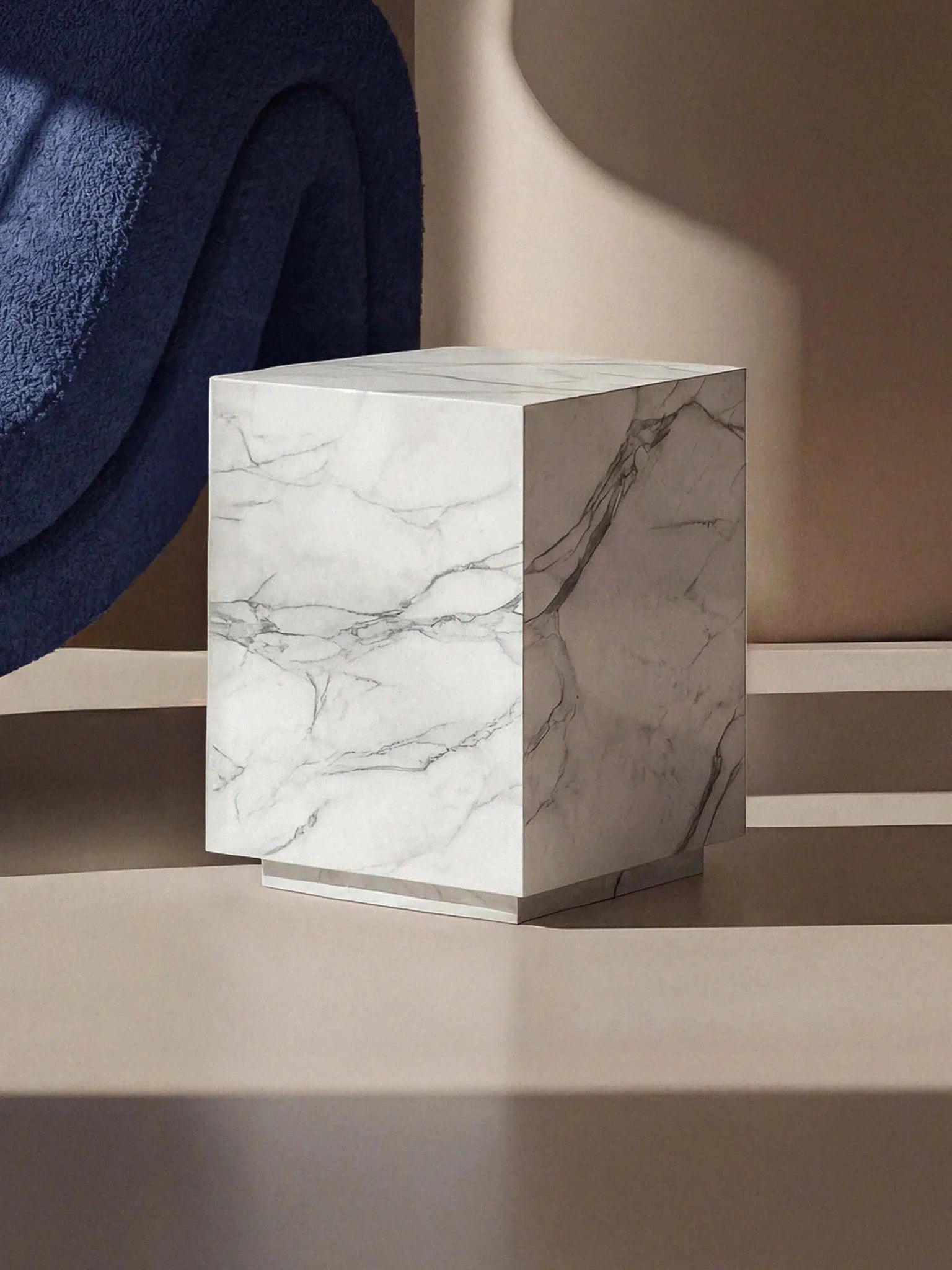 Kubischer Beistelltisch Pella aus edlem Calacatta White Marmor in einer modernen Raumsituation mit blauem Farbakzent.