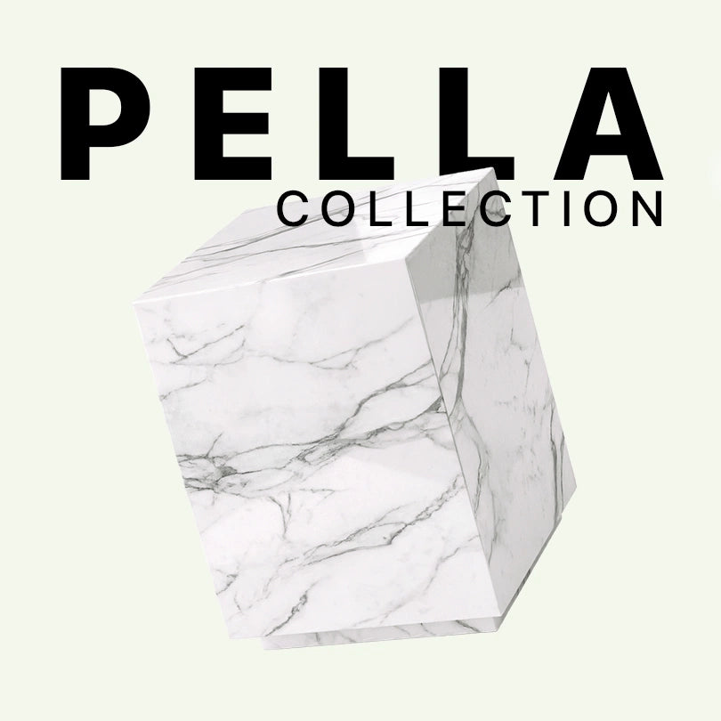 Werbebild der Pella Collection von Menelame. Abgebildet ist der monolithische Beistelltisch aus weißem Calacatta Marmor mit seiner eleganten, fließenden grauen Äderung vor einem hellen Hintergrund mit Markenschriftzug.