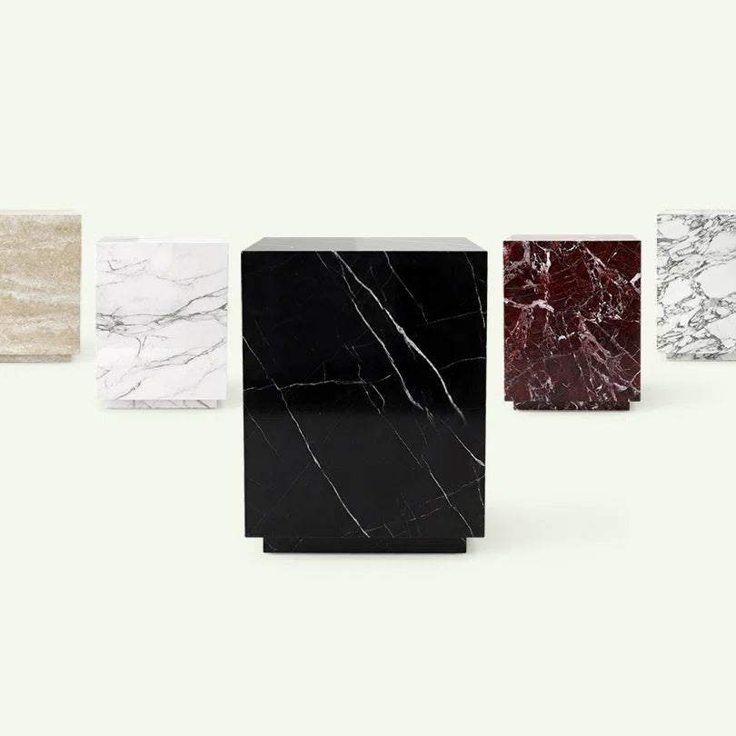 Frontale Materialübersicht der Pella Serie. Im Zentrum steht die Variante aus schwarzem Nero Marquina Marmor, flankiert von den Modellen in Rosso Levante, Calacatta White, beigem Travertin und Arabescato zur Veranschaulichung der Materialvielfalt.