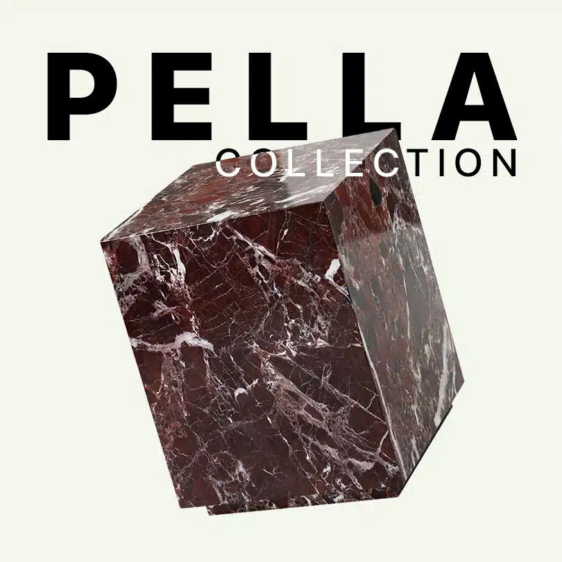 Werbegrafik für den Pella Beistelltisch aus Rosso Levanto Marmor. Das Bild zeigt den kubischen Natursteintisch mit seiner tiefroten Grundfarbe und den markanten weißen Einschlüssen unter dem Schriftzug „Pella Collection“.