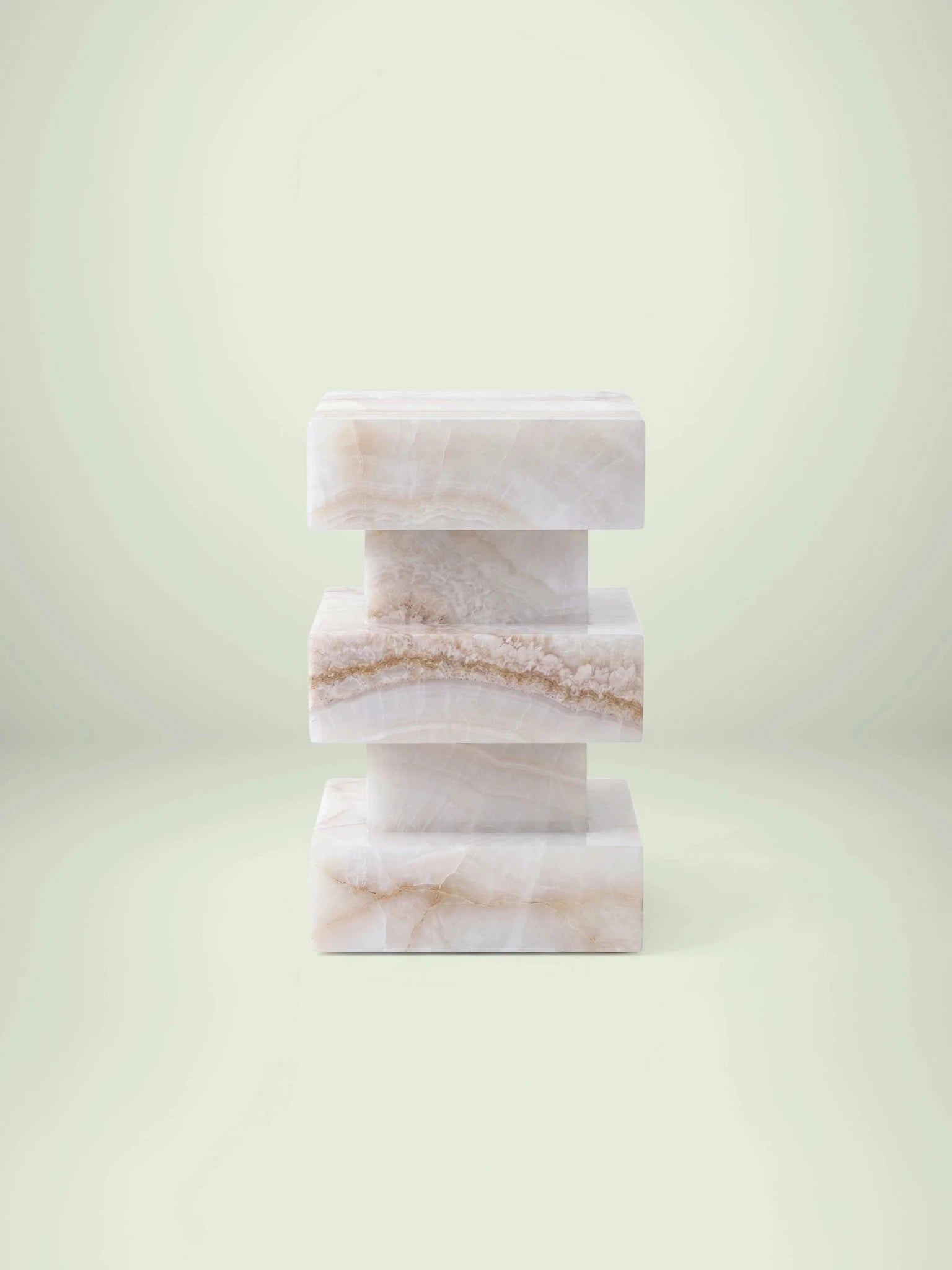 Frontalansicht des Beistelltischs Monue aus weißem Onyx mit einem markanten, gestuften Säulendesign.