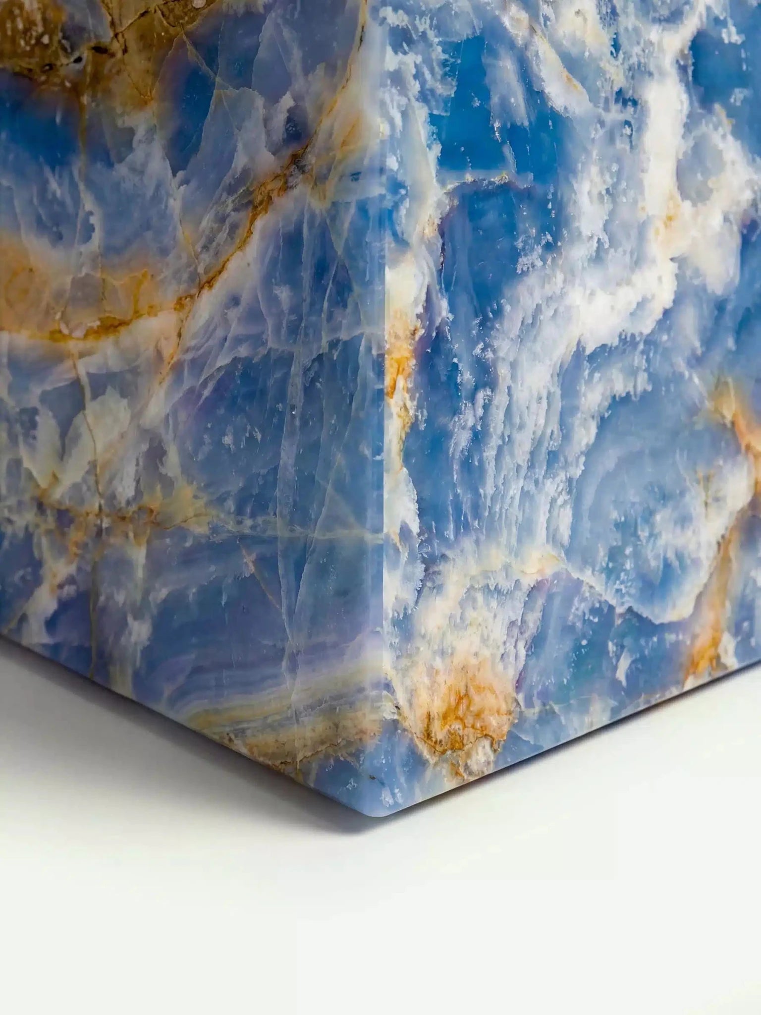 Detailaufnahme der unteren Ecke des Modells Suela, die die intensiven Blau- und Weißtöne des natürlichen Onyx-Steins hervorhebt.