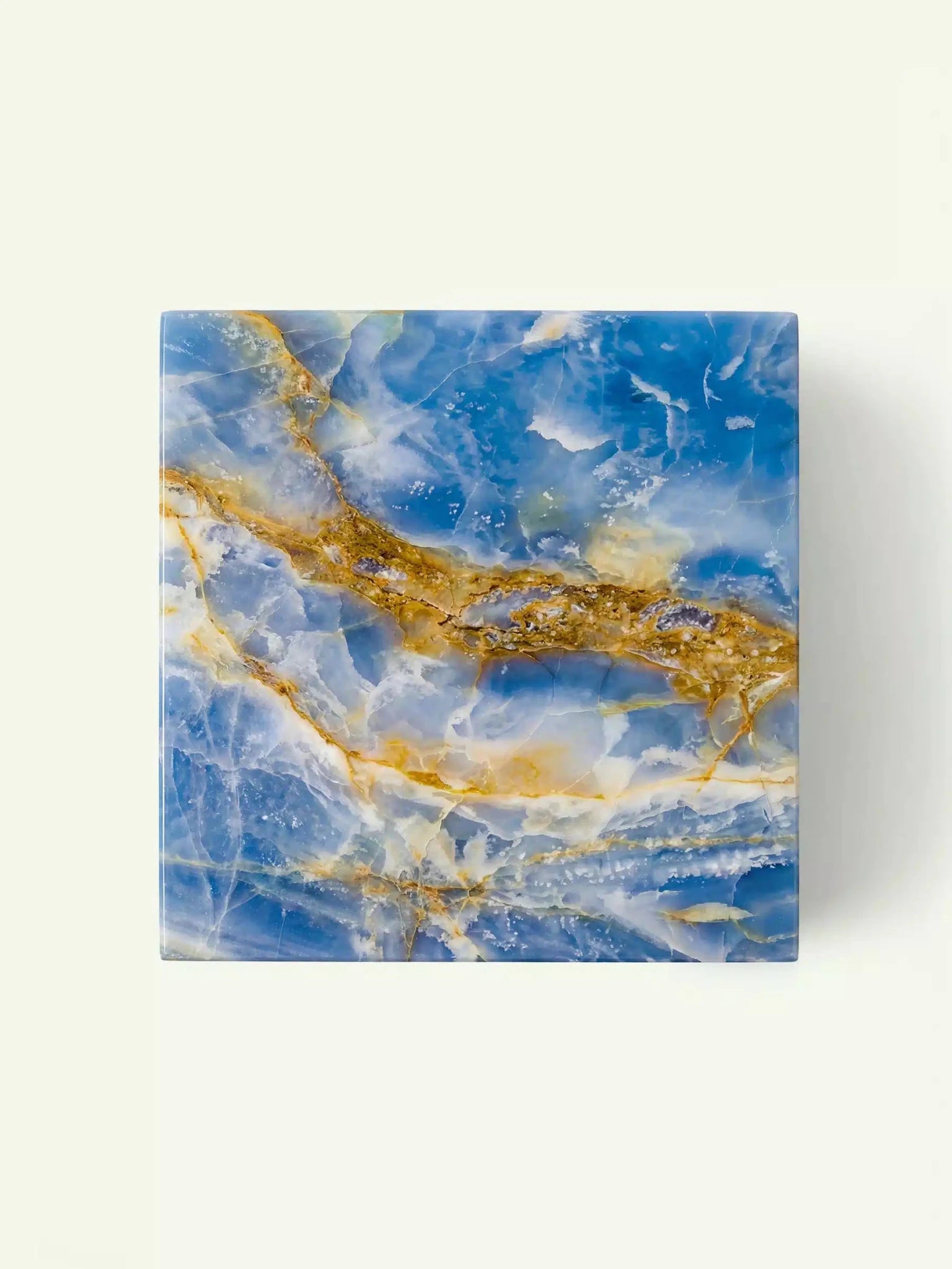 Blick von oben auf die quadratische Tischplatte des Modells Suela aus blauem Onyx mit seiner einzigartigen, wolkenartigen Maserung.