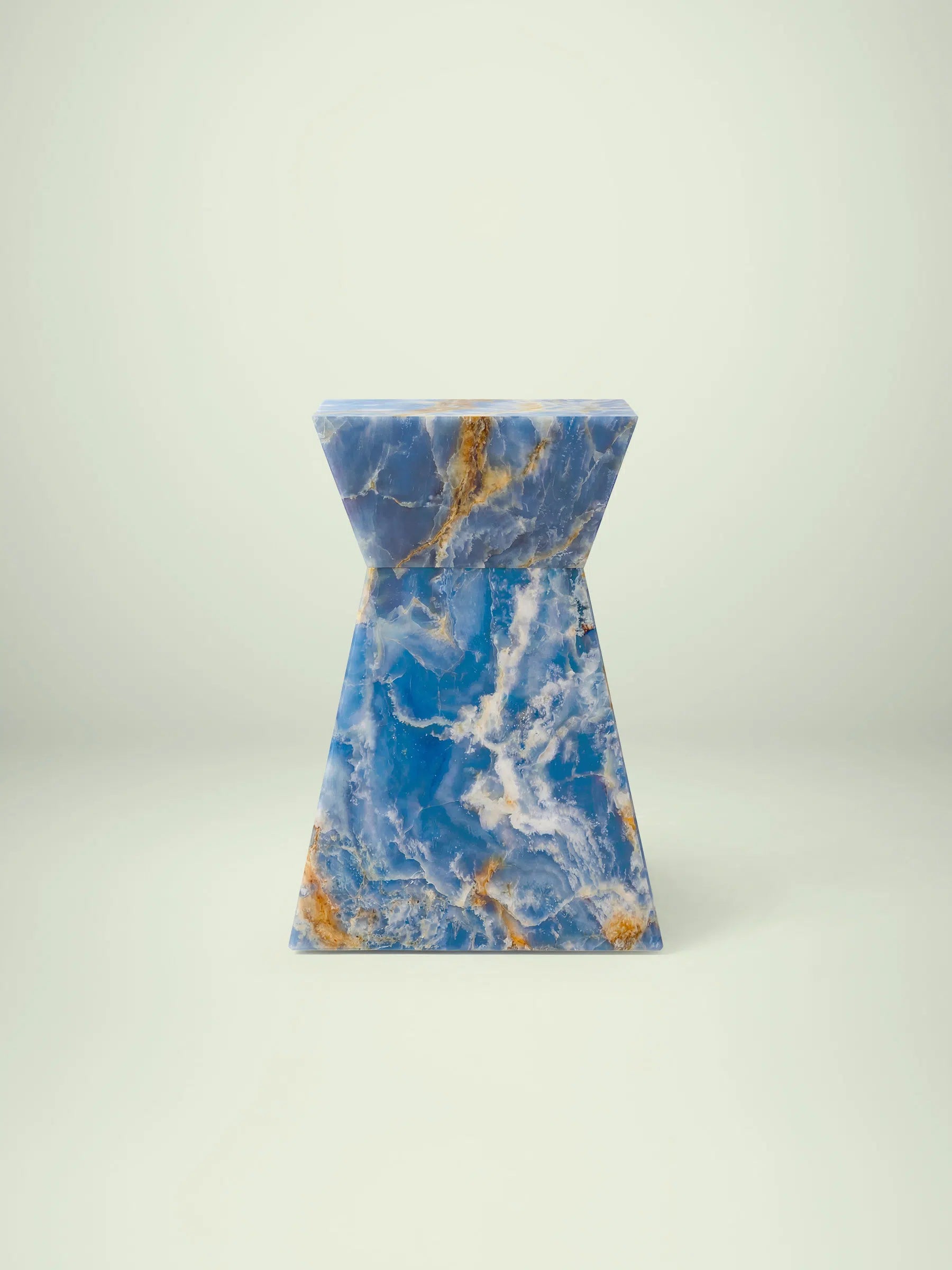 Frontalansicht des exklusiven Beistelltischs Suela aus blauem Onyx mit markanter Sanduhren-Form und goldbraunen Akzenten.