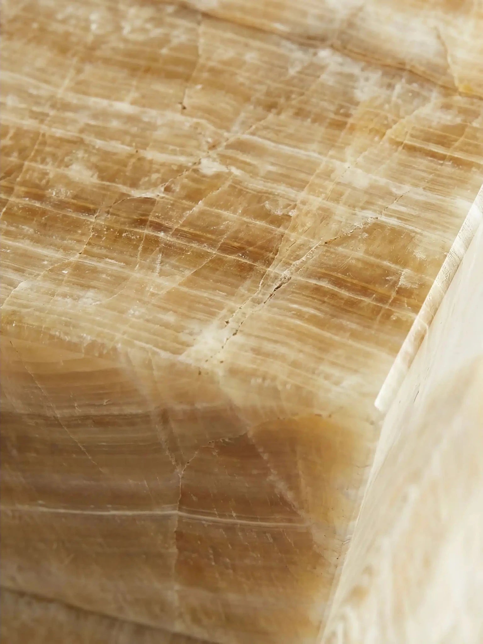 Detailaufnahme der Oberfläche des Honig-Onyx, die die feinen Schichten und die Tiefe des Natursteins verdeutlicht.