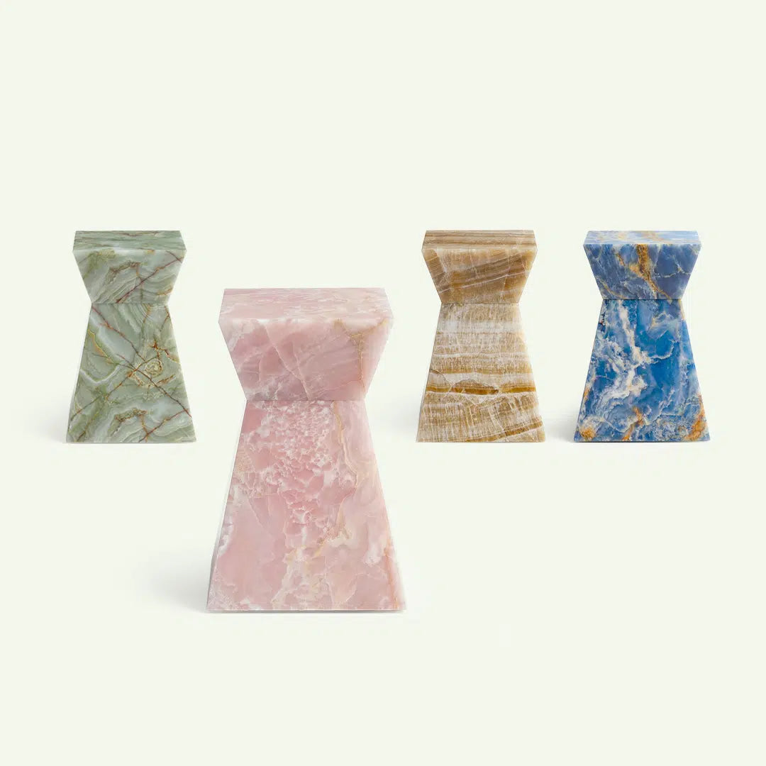 Frontale Übersicht der Suela Onyx-Serie. Im Zentrum steht die Variante in Rose Onyx, im Hintergrund sind die Modelle in grünem Onyx, Honig-Onyx und blauem Onyx aufgereiht, um die verschiedenen Farboptionen der Kollektion zu präsentieren.