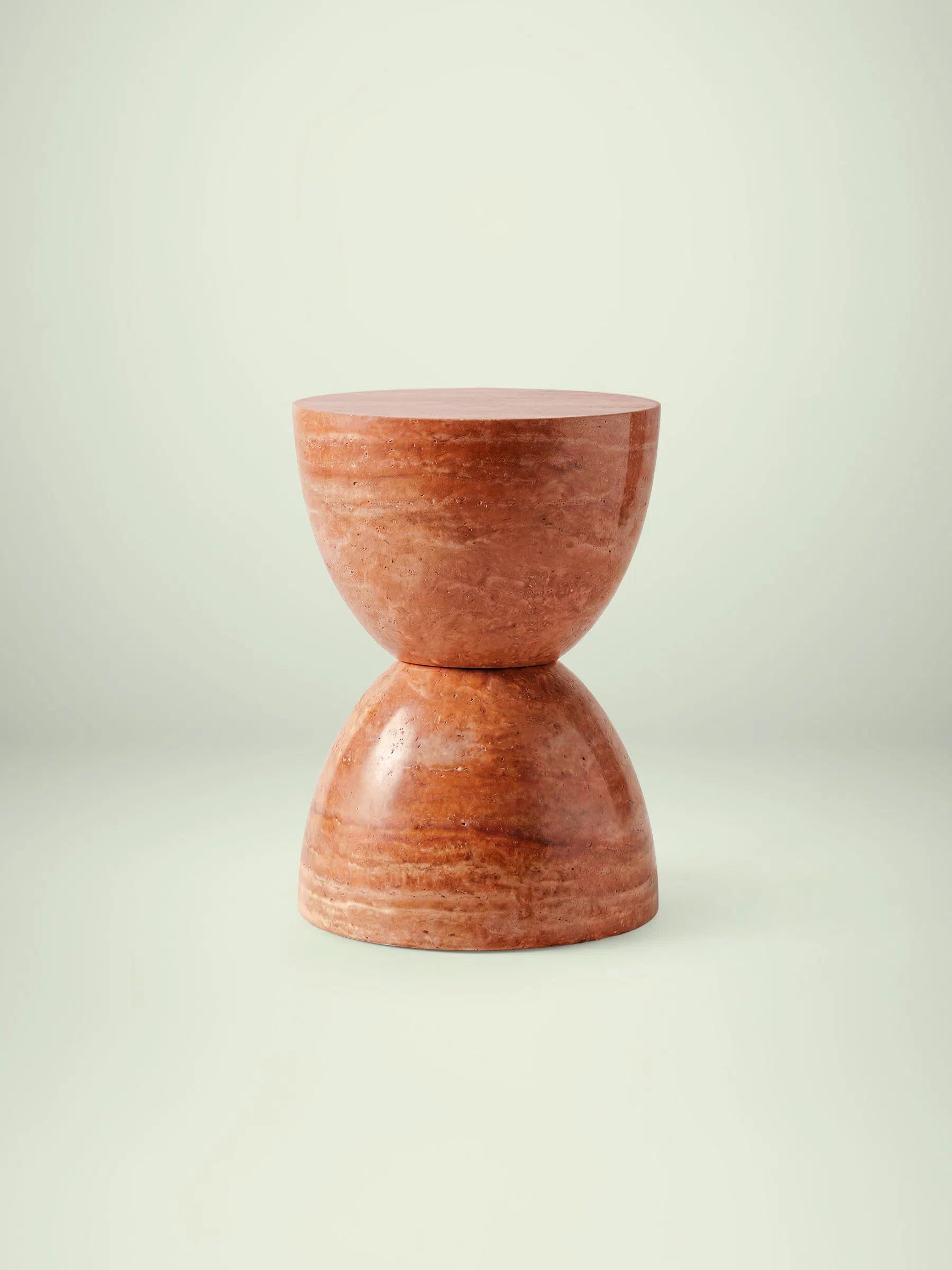 Frontalansicht des Beistelltischs Kromi aus rotem Travertin in skulpturaler Sanduhren-Form.