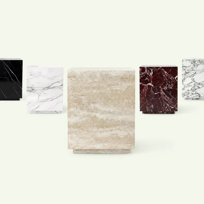 Frontale Materialübersicht der Pella Serie. Im Zentrum steht die Ausführung in beigem Travertin, im Hintergrund sind die Varianten in Nero Marquina, Calacatta White, Rosso Levante und Arabescato aufgereiht.