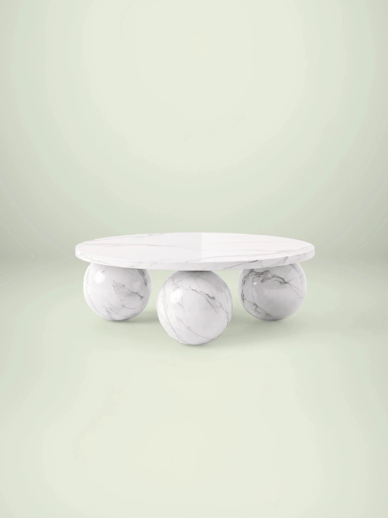 Frontalansicht des niedrigen Couchtischs Belnor aus Calacatta White Marmor mit drei markanten Kugelfüßen.