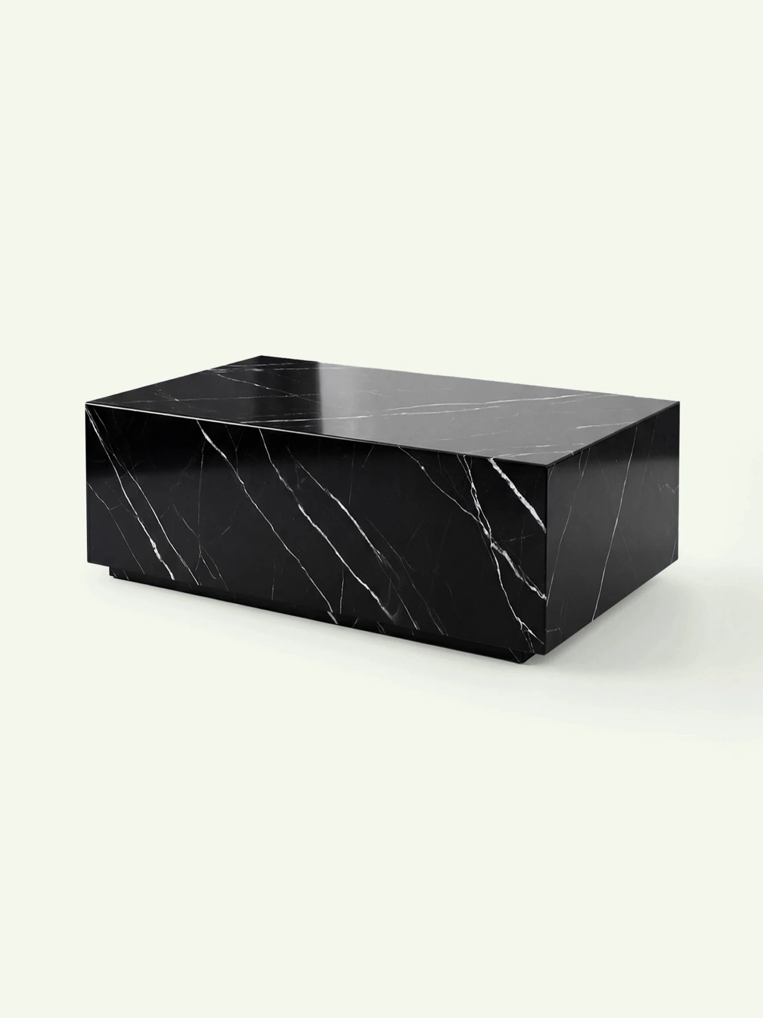 Dreiviertelansicht des Madena Couchtischs von Menelame. Die perspektivische Darstellung zeigt die kubische Form und den leicht eingerückten Sockel des massiven Nero Marquina Marmortischs.