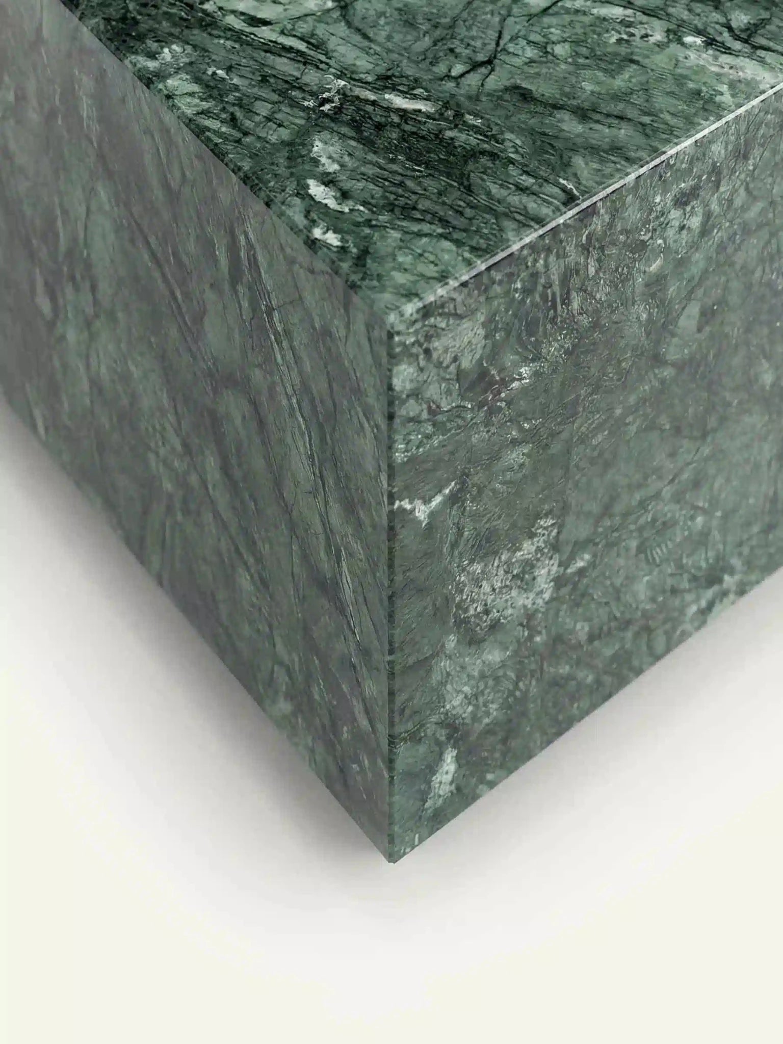 Nahaufnahme einer Tischecke des Madena Couchtischs. Die Ansicht verdeutlicht die hochwertige Gehrungsarbeit und die dichte, kristalline Struktur des Verde Guatemala Marmors an der Oberflächenkante.