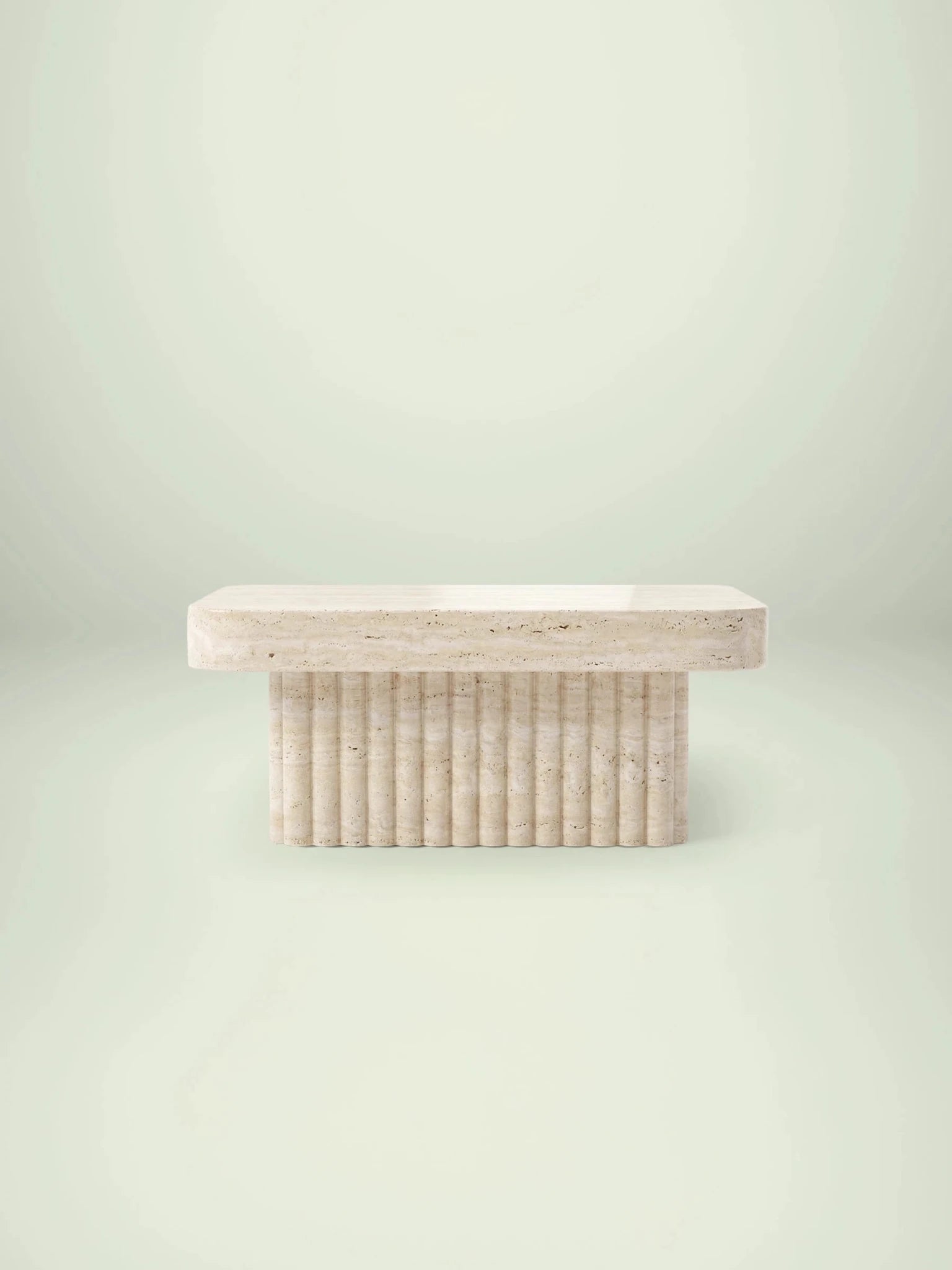 Frontale Studioansicht des quadratischen Kutio Couchtischs von Menelame. Der beige Travertin-Tisch zeigt eine massive Platte mit abgerundeten Ecken auf einem skulpturalen, geriffelten Sockeldesign.