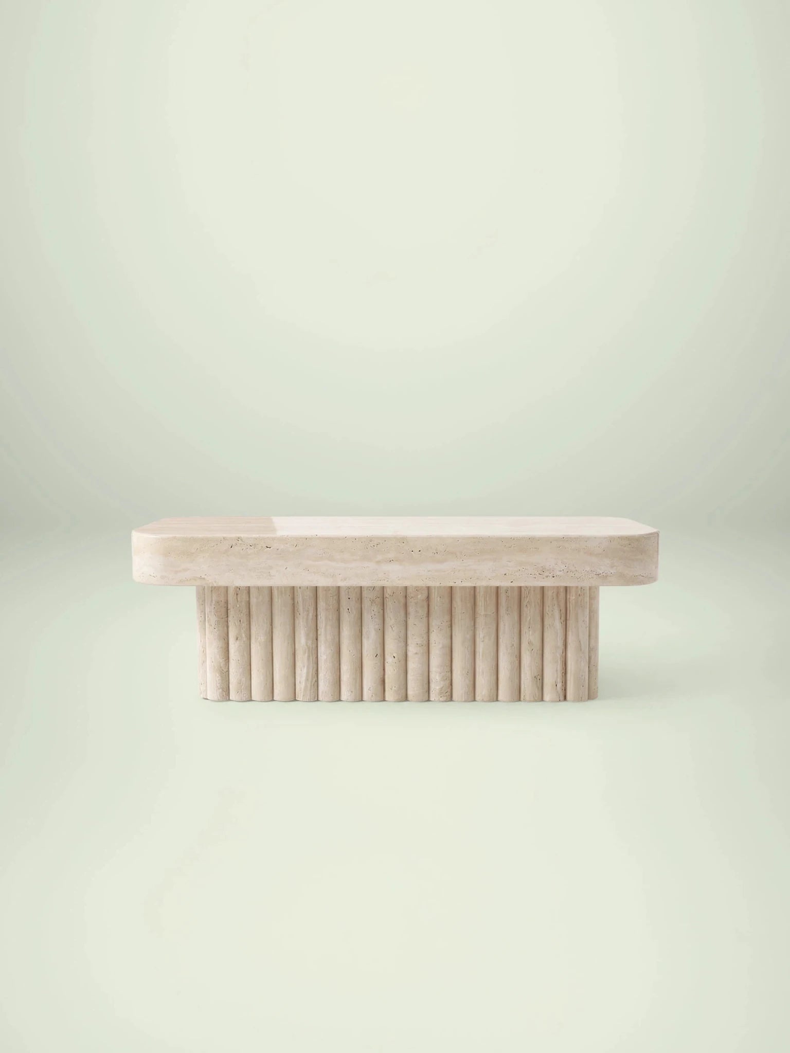 Frontale Ansicht des Kutiu Couchtischs von Menelame aus beigem Travertin. Das Design besticht durch eine dicke, rechteckige Tischplatte mit abgerundeten Ecken und einen markanten geriffelten Sockel in Säulen-Optik.