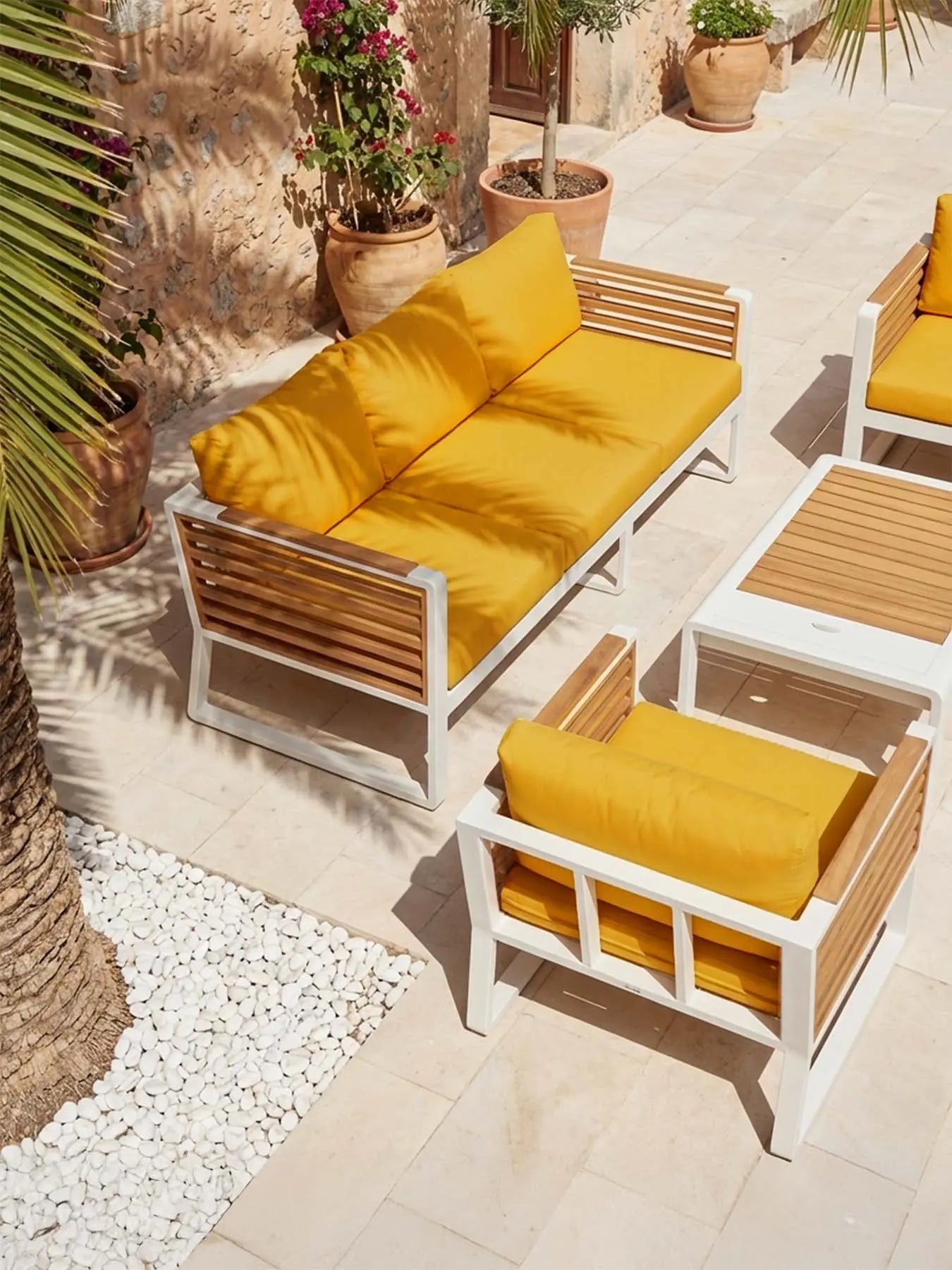 Stimmungsvolle Draufsicht auf die Menelamé Balin Lounge-Möbel in Honiggelb auf einer sonnigen Terrasse.