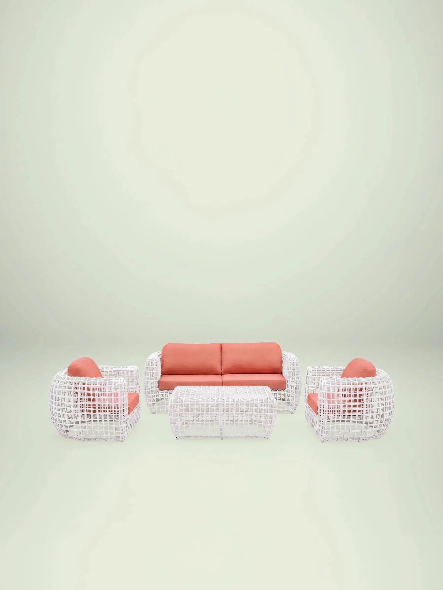 Menelamé Outdoor Lounge-Set Durnes bestehend aus weißem Rattan-Sofa und Sesseln mit korallenroten Olefin-Kissen.