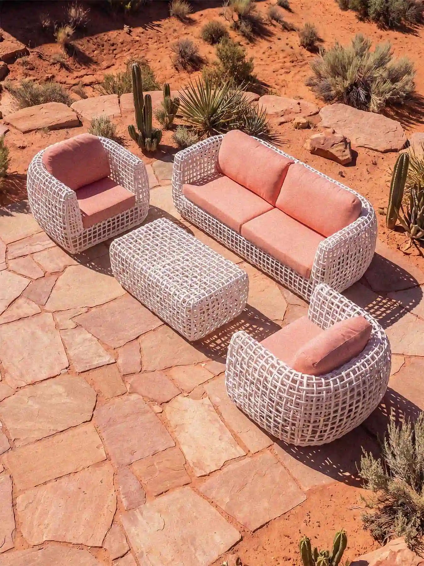 Perspektivische Lifestyle-Aufnahme der Menelamé Durnes Outdoor-Möbel mit Fokus auf das Design-Geflecht und die roten Polster.