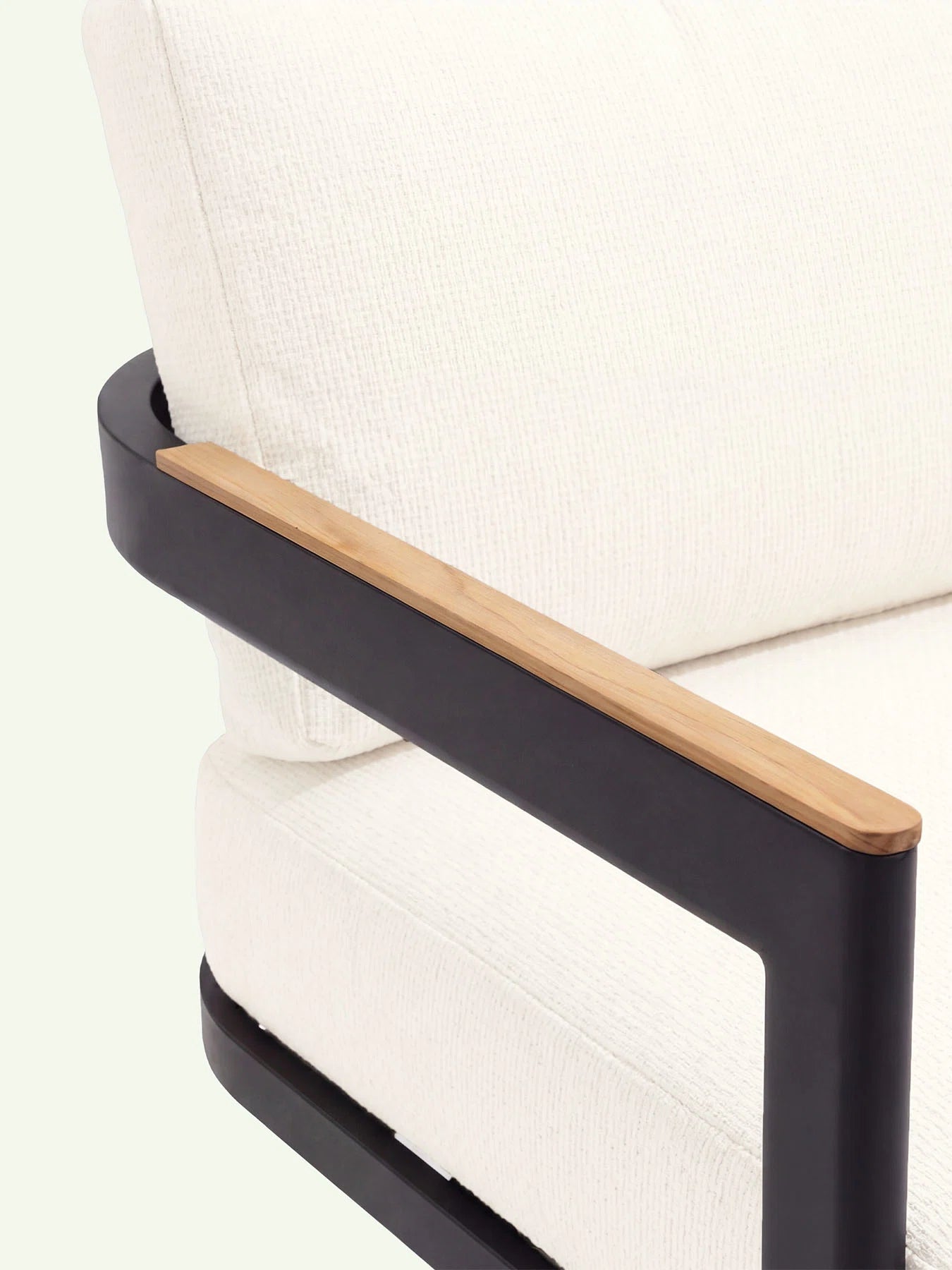 Detailaufnahme Menelamé Holla: Teakholz-Armlehne auf schwarzem Aluminium und schneeweißer wetterfester Olefin-Stoff.