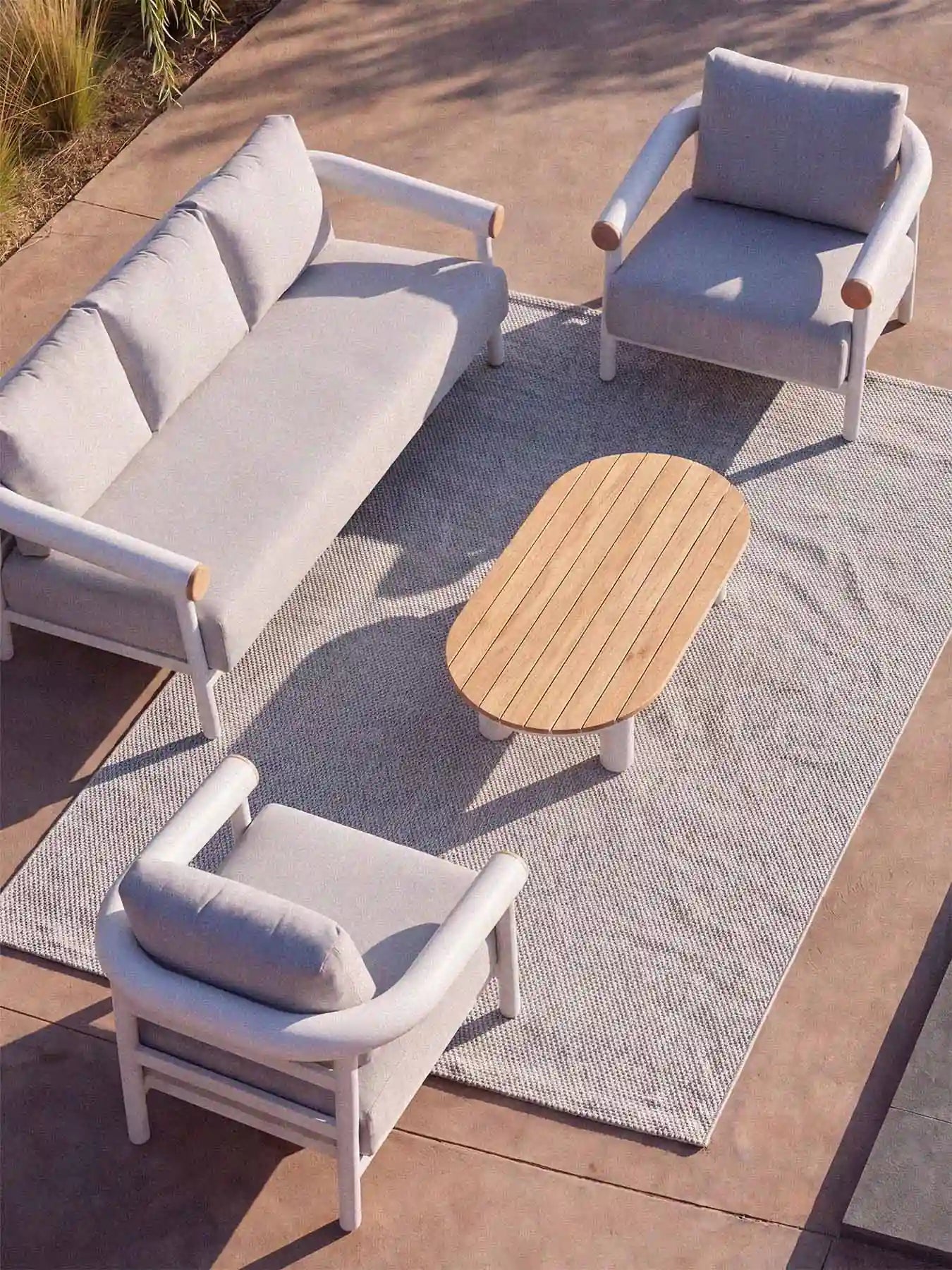 Perspektivische Draufsicht der Menelamé Kanunu Sitzgruppe auf einer Terrasse, modernes Design-Geflecht und Holz-Tischplatte.