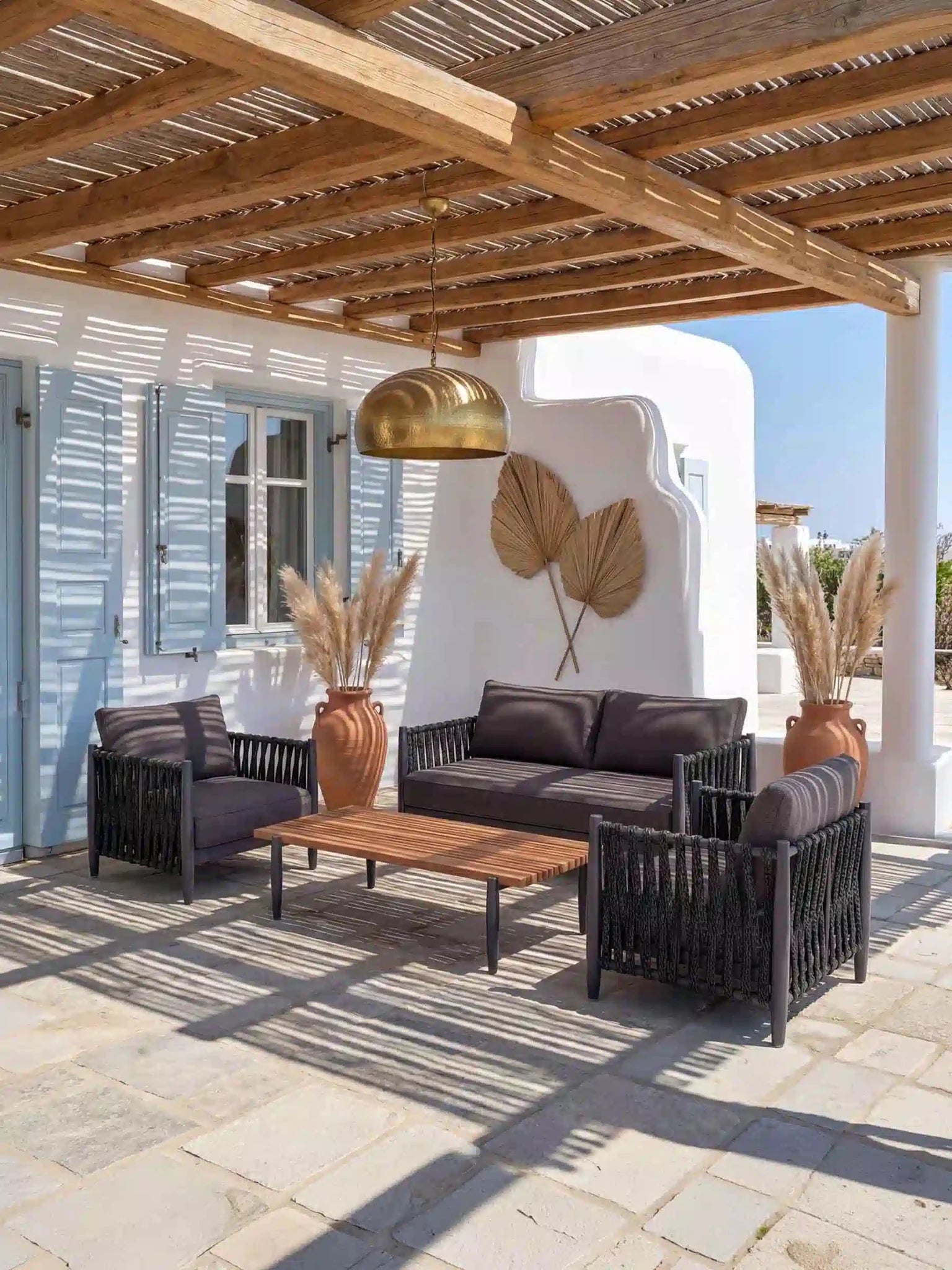 Luxuriöse Menelamé Skron Outdoor-Lounge auf einer sonnigen Terrasse im mediterranen Stil mit Blick auf den Pool.