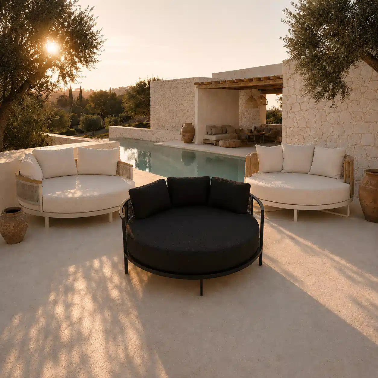 Menelamé Shop by Look: Drei exklusive, runde Luxus-Daybeds in Anthrazit und Cremeweiß auf einer minimalistischen Steinterrasse mit Infinity-Pool bei Sonnenuntergang.