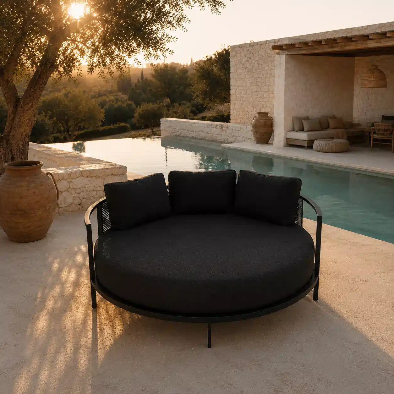 Menelamé Shop by Look – Luron Sonneninsel: Luxuriöses, rundes Design-Daybed in Schwarz an einem Infinity-Pool während der goldenen Stunde.