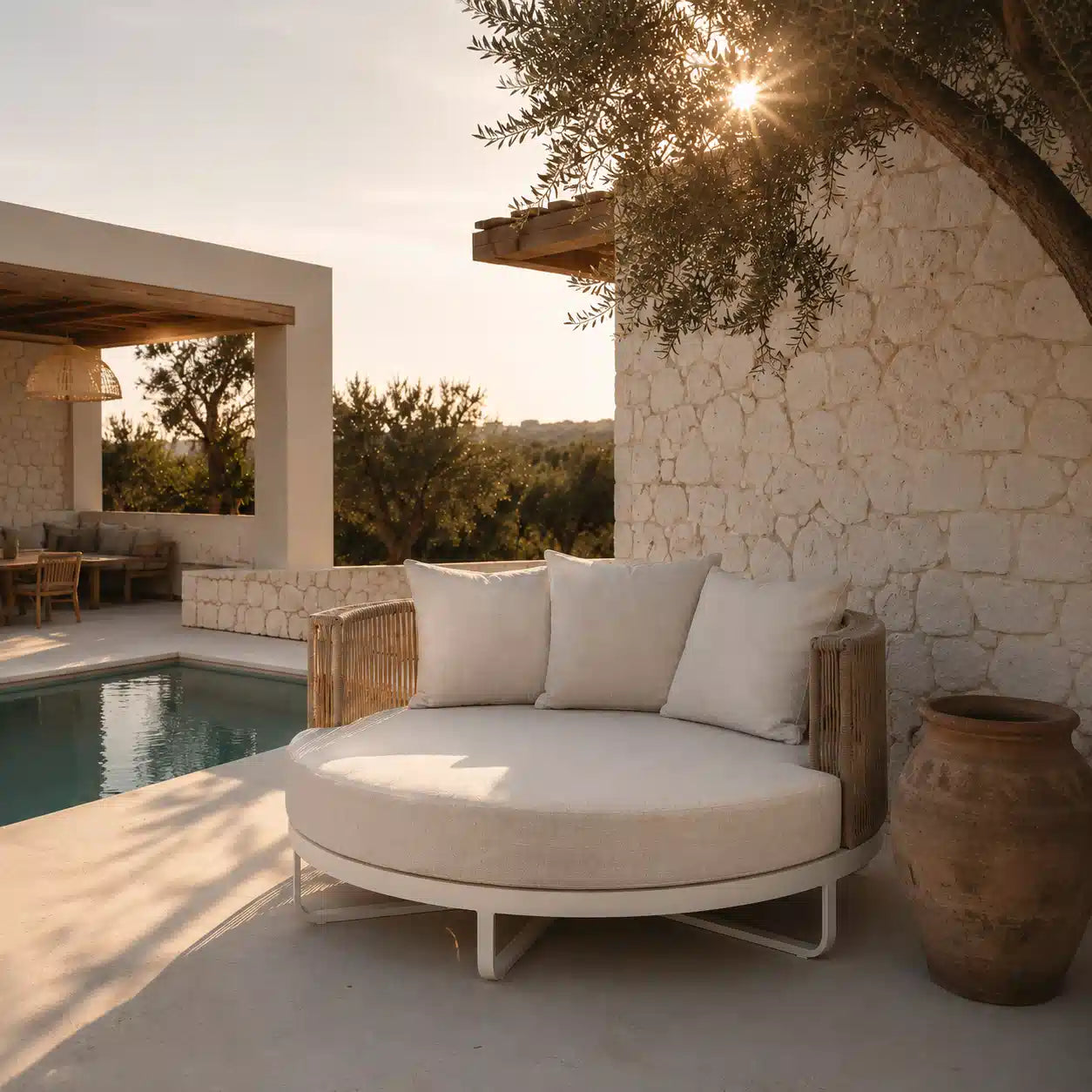Menelamé Shop by Look – Malesa Sonneninsel: Minimalistisches, rundes Outdoor-Daybed in Cremeweiß mit eleganter Seilflechtung an einer mediterranen Natursteinwand.